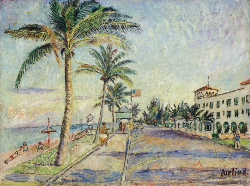 Oceanside landscape with palm alley and sandy beach on the left and white houses on the right, full of sunlight with a blue sky. 