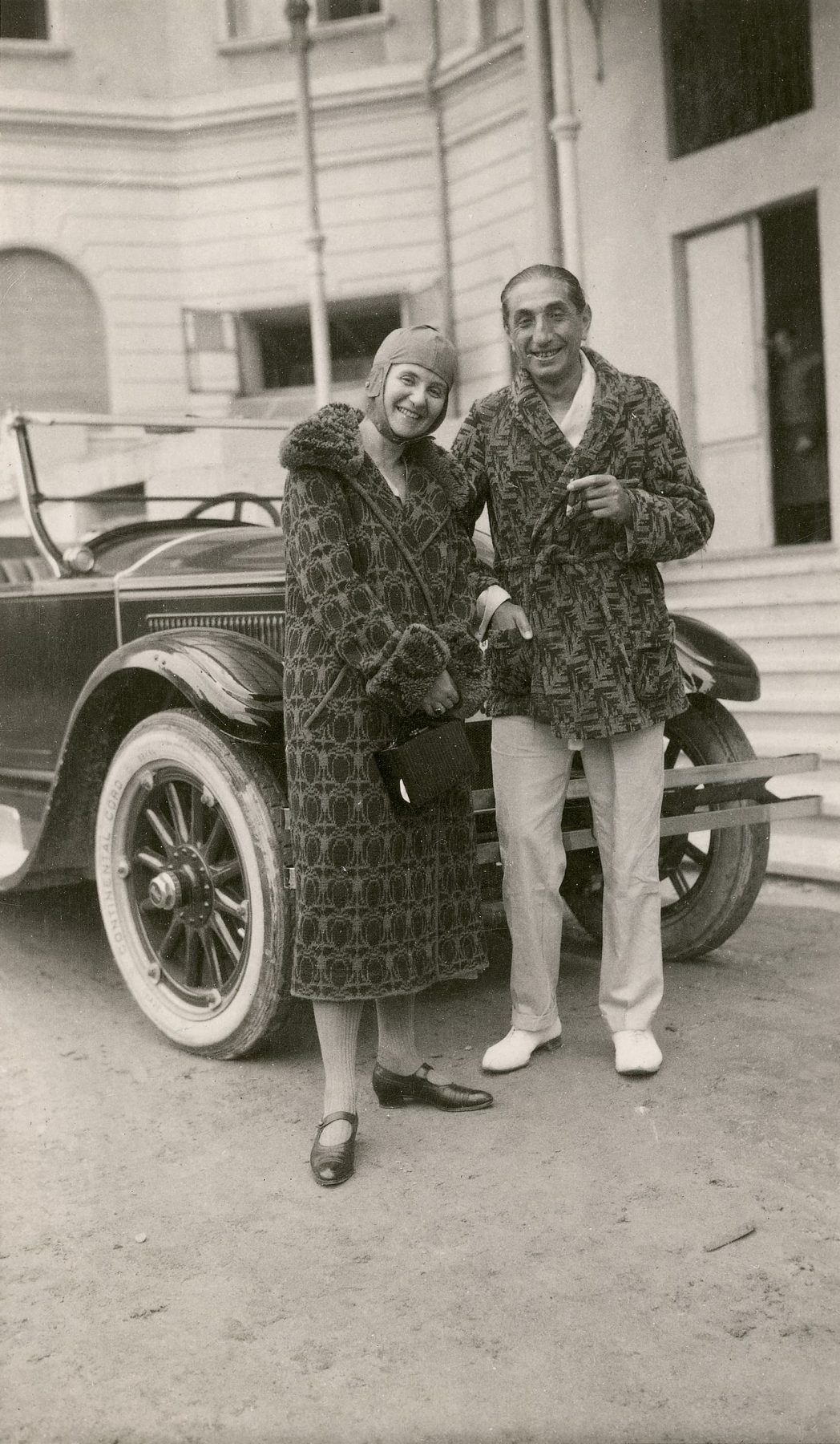 Historisches Schwarzweißfoto von einer Frau und einem Mann vor einem Oldtimer-Auto
