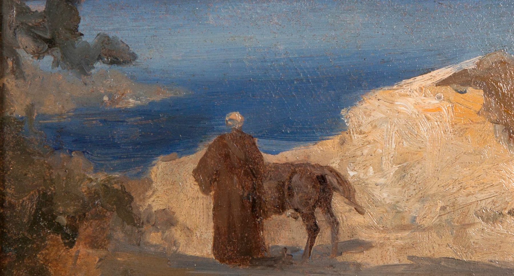 Ein Mönch mit brauner Kutte steht mit dem Rücken zum Betrachter und einem Esel neben ihn vor dem Meer umgeben von hell angstrahltem Sand.