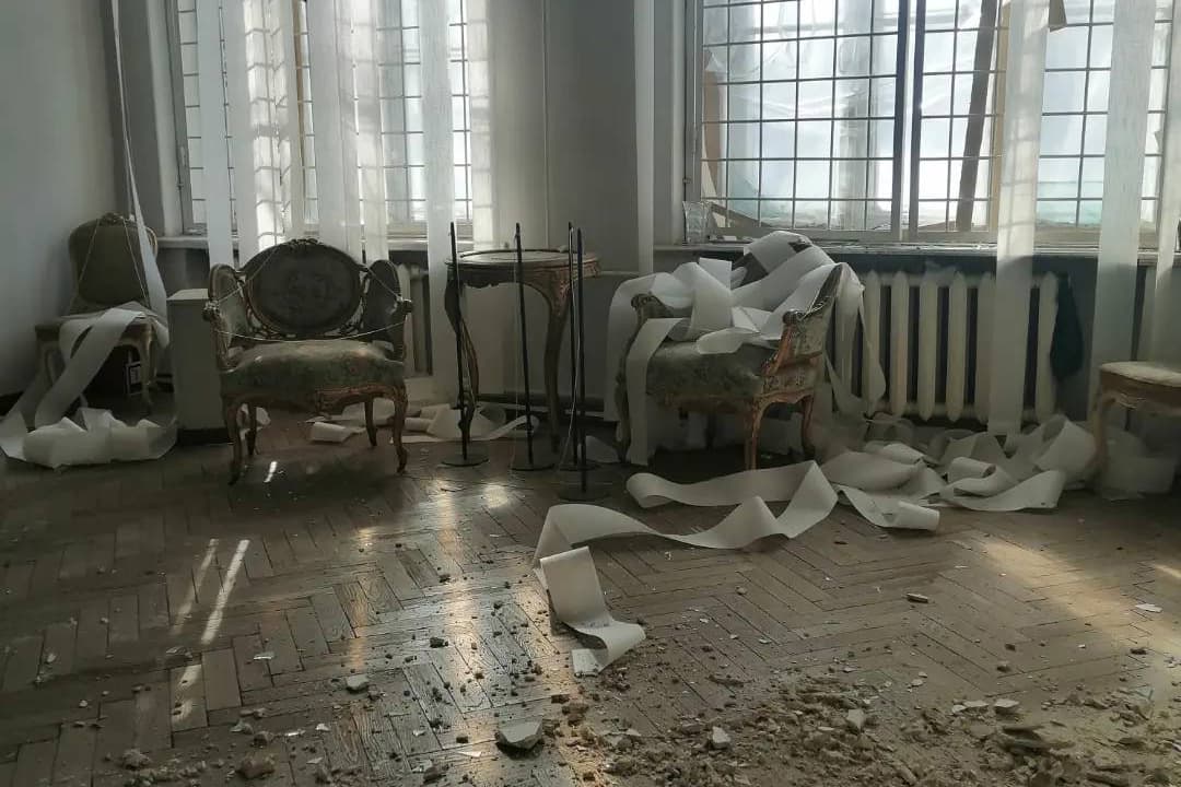 Foto der Zerstörung des Kunstmuseums Charkiw mit heruntergrochenen Wandstücken auf historischen Möbeln