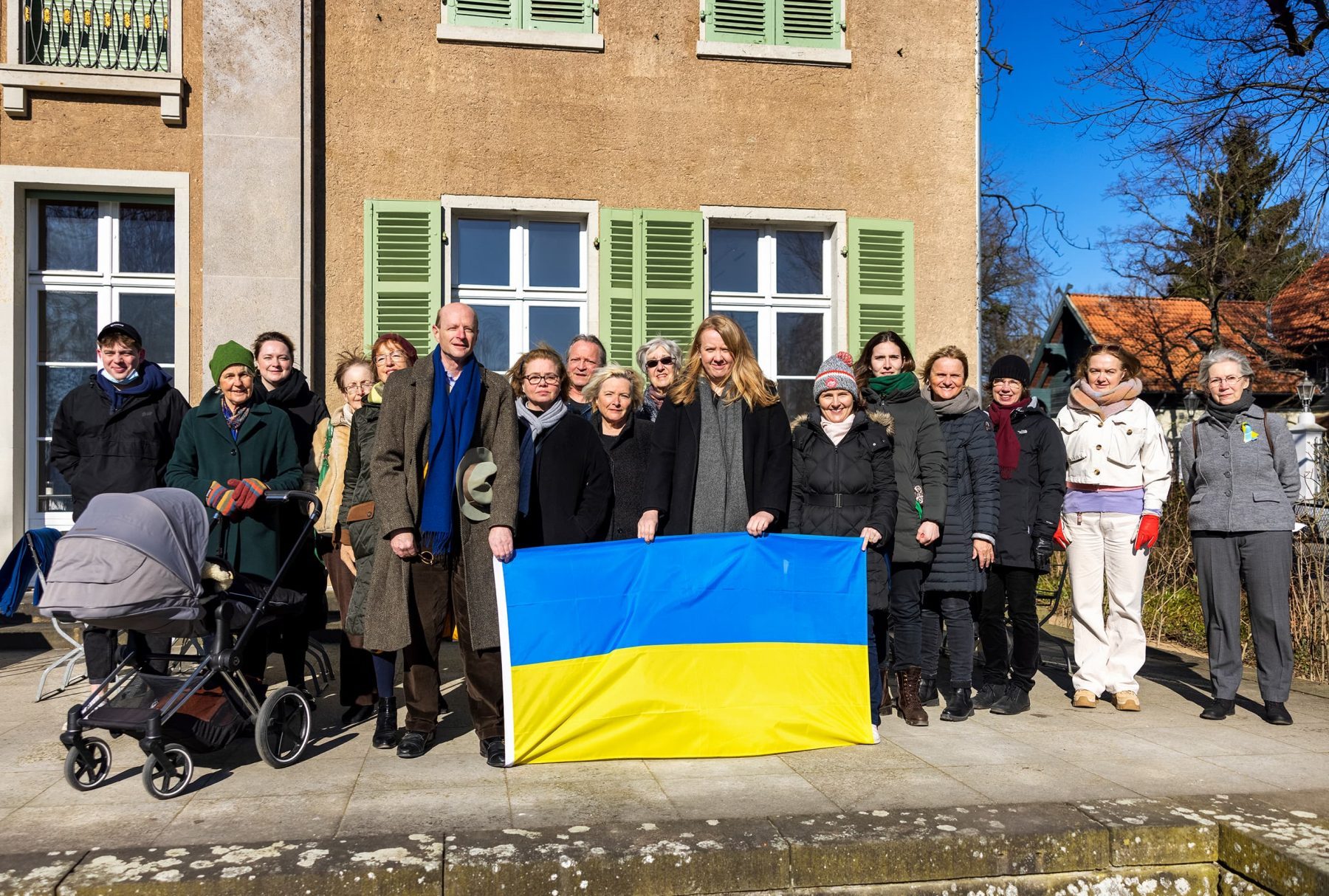 Gruppenfoto von mehreren Personen, die im Vordergrund eine ukrainische Flagge mit Blau und gelben Streifen halten.