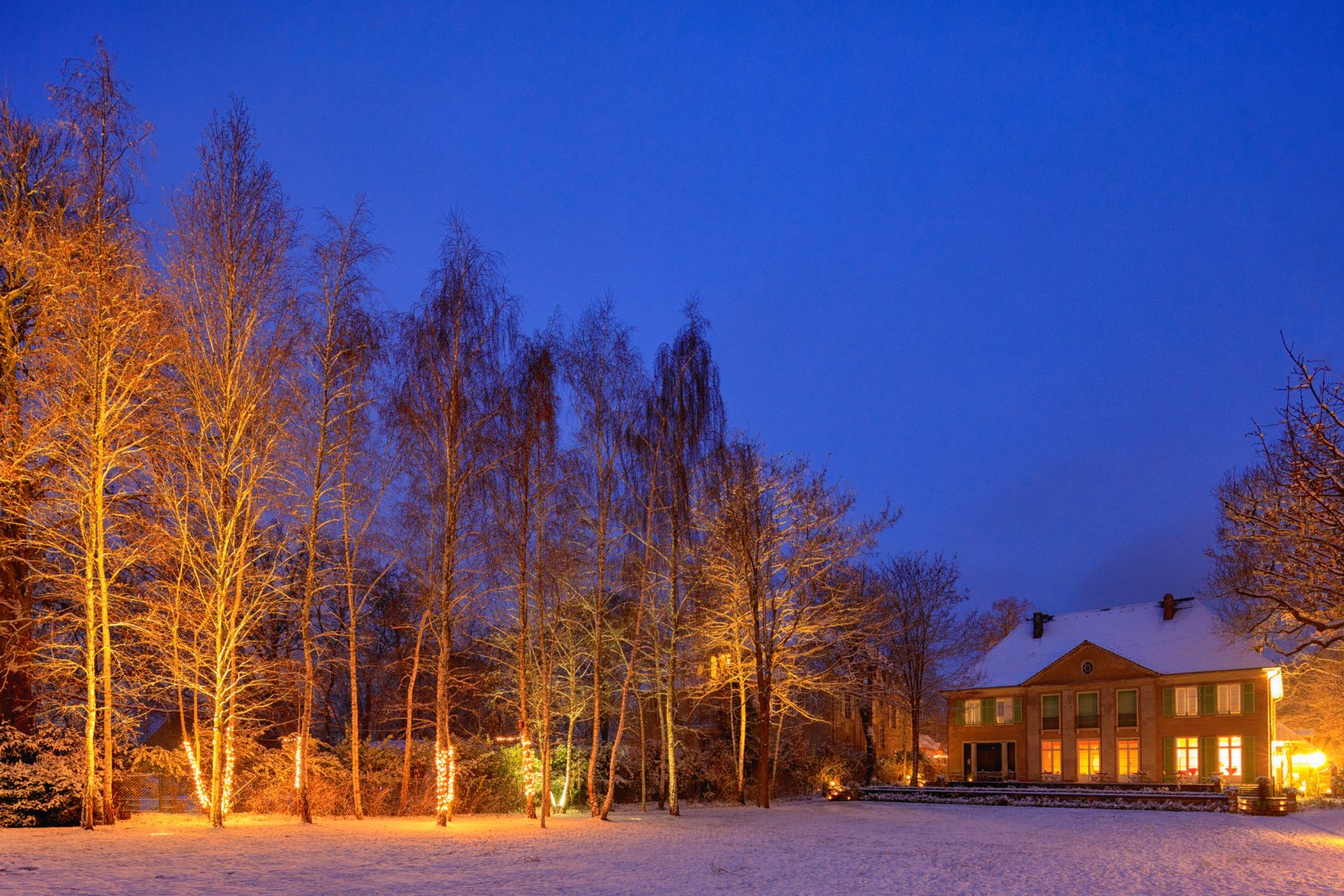Ein aktuelles Foto des Gartens der Liebermann-Villa im Winter mit Schnee und Beleuchtung.