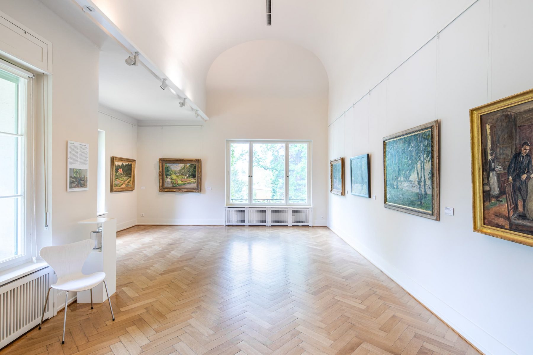Raumansicht von weißen Wänden mit mehreren Gemälden.
