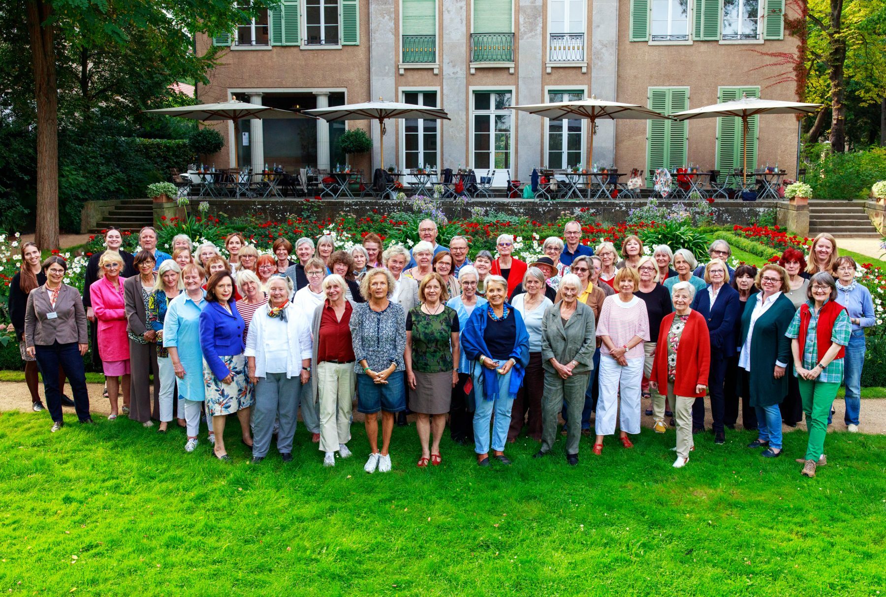 Großes Gruppenfoto mit über 70 Personen, die auf der Wiese vor der Liebermann-Villa stehen und in die Kamera lächeln.
