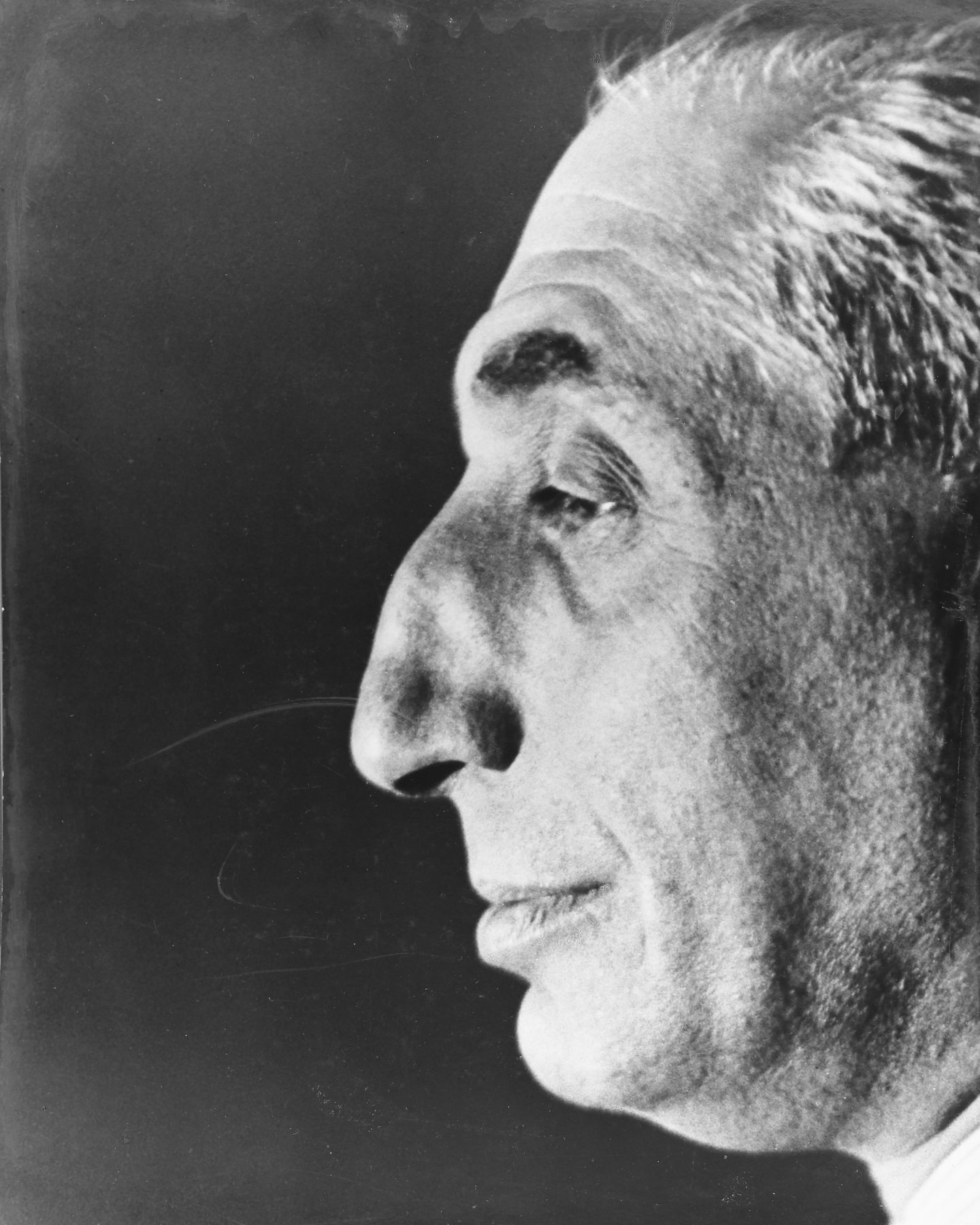 Auf dem Porträt ist Alfred Flechtheims markantes Gesicht im Profil zu sehen. Die Details seiner Physiognomie stechen im Kontrast zu dem dunklen Hintergrund stark hervor.