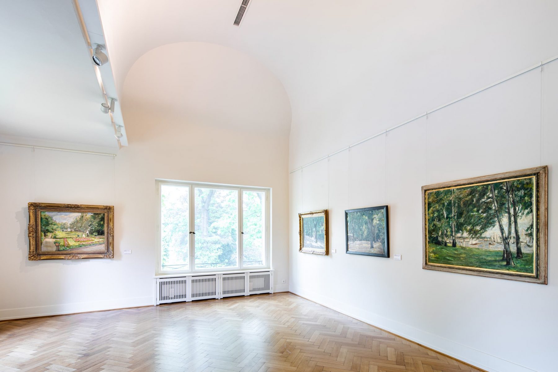 Raumansicht von weißen Wänden mit mehreren Gemälden.